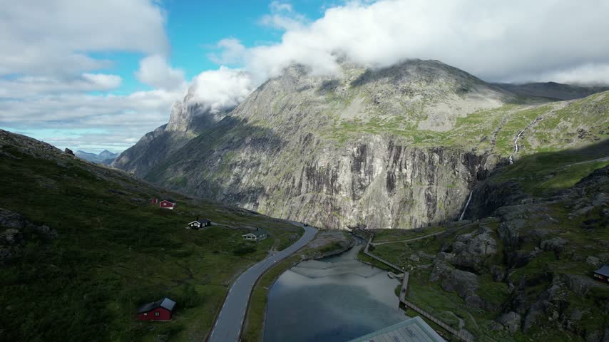 Trollstigen viewpoint with cliffs and clouds, aerial pull-back, Møre og Romsdal, Norway, filmed on a sunny summer day.