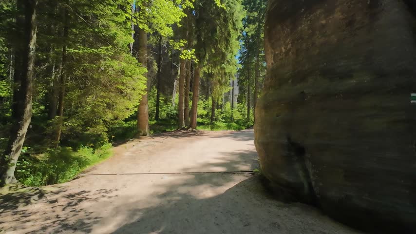 Wide hiking trail with wooden railing and sandstone rocks in Adrspach forest, Czech Republic