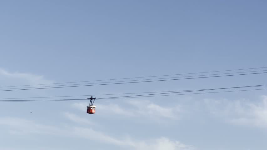 Red tourist cable car moving across a clear blue sky in Barcelona, Catalonia