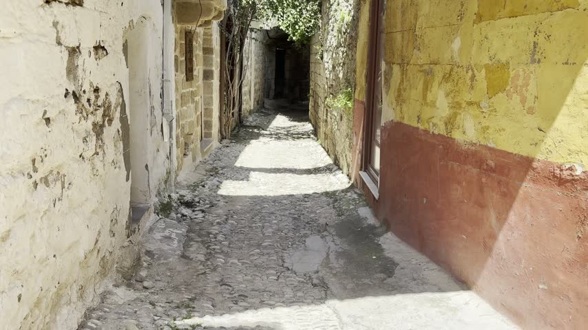 Narrow alley with stone arches and colorful walls in the Old Town of Rhodes, Greece