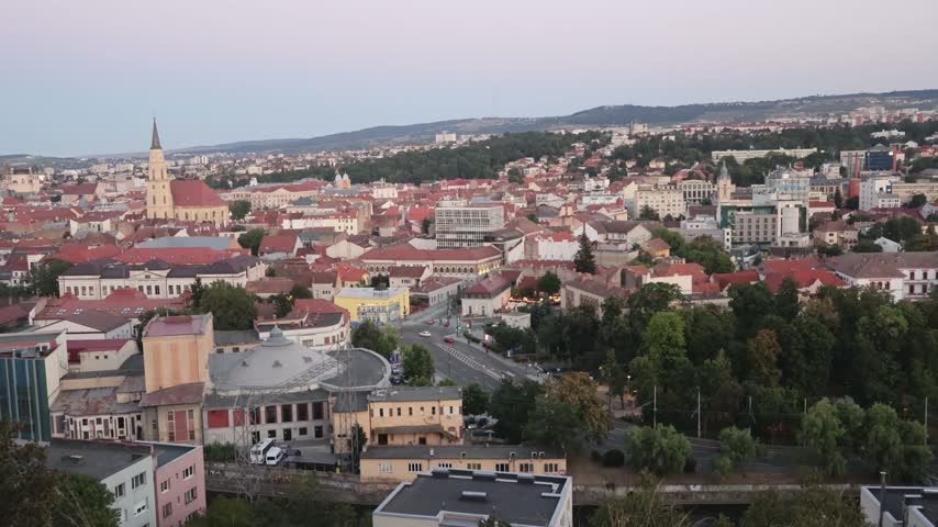 Elevated panoramic view of Cluj-Napoca with historic rooftops and Saint Michael’s Church beneath a soft evening sky