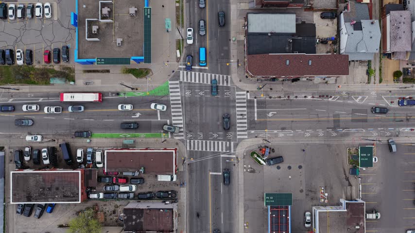 Top down view of an intersection with bike lanes, crosswalks, buses and trucks in Toronto Canada, cars tracked by hexagon tags and speed labels, smart city traffic HUD overlay with sensor nodes