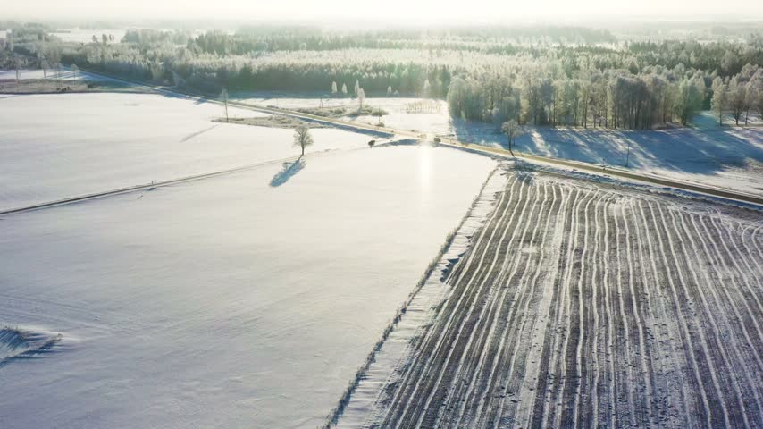 Aerial view of a bright winter morning with snow-covered fields and a country road