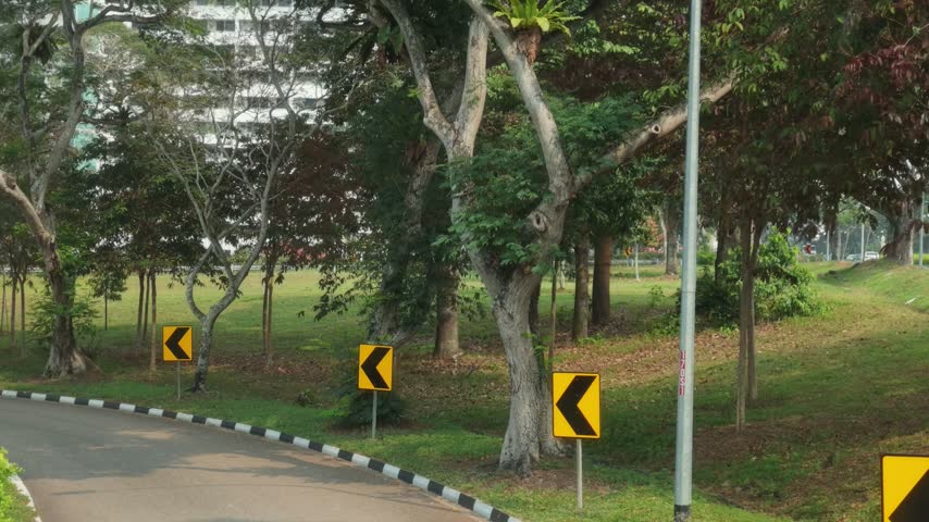 A first-person perspective view of highway in Singapore, showcasing flowing vehicle traffic with roadside greenery and clean modern infrastructure.