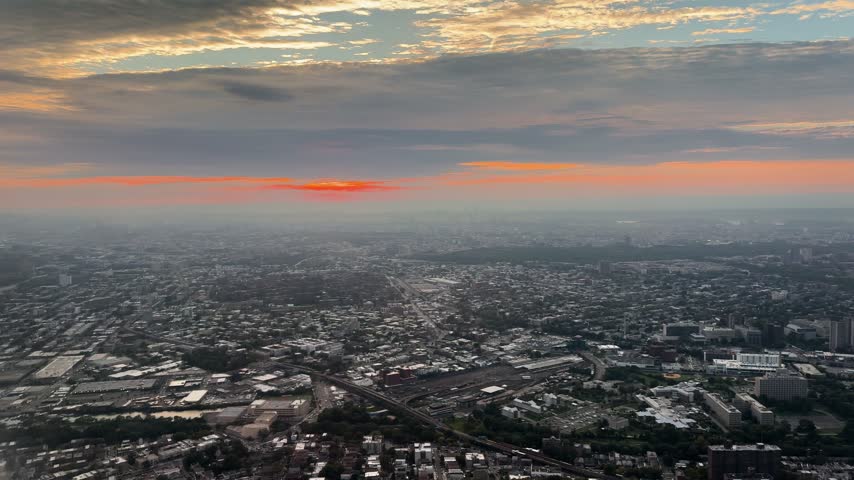Aerial view over New York City at sunset with dramatic clouds and cityscape below
