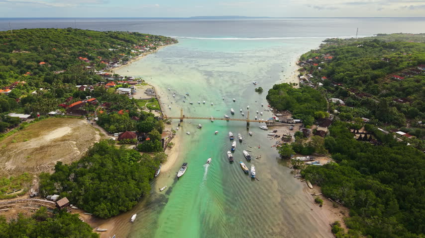 Drone camera flying forward over a scenic suspension bridge and shallow marine channel, popular travel destination for sightseeing and island hopping