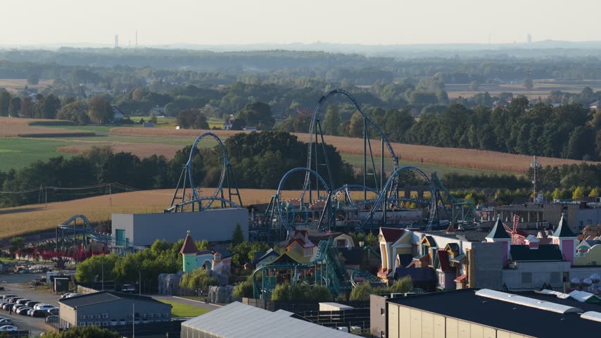Roller coaster descending a steep track at an amusement park in Poland, with excited people experiencing an intense thrill ride, funfair attractions and adrenaline filled entertainment.