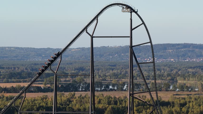 Roller coaster descending a steep track at an amusement park in Poland, with excited people experiencing an intense thrill ride, funfair attractions and adrenaline filled entertainment.