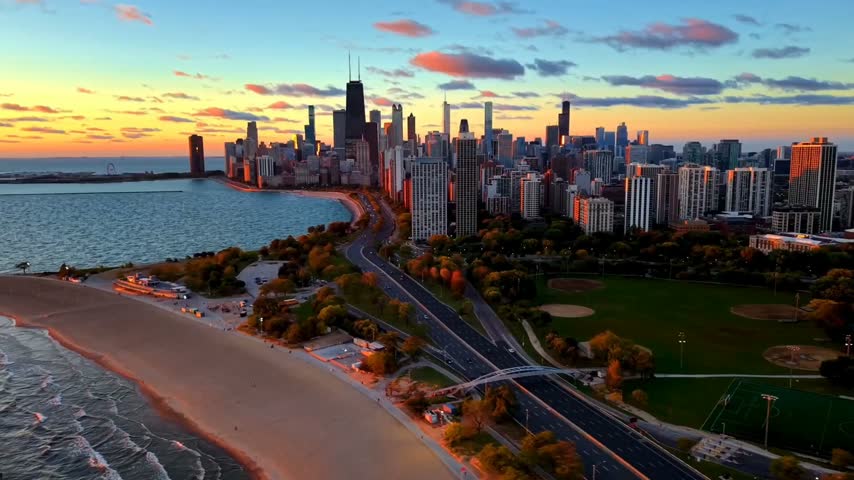 Cinematic aerial view of the Chicago skyline along Lake Michigan during a colorful sunset. Downtown skyscrapers, sandy beach, waterfront roads, green parks, and city architecture create a stunning urban landscape. Beautiful golden hour lighting, vibrant clouds, and scenic lakeshore views showcase the beauty of Chicago, Illinois, USA. Ideal for travel, tourism, real estate, city lifestyle, urban development, and commercial video projects.