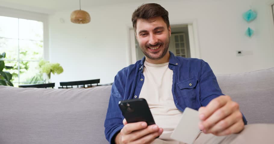 Man holding a blank card up in a bright living room