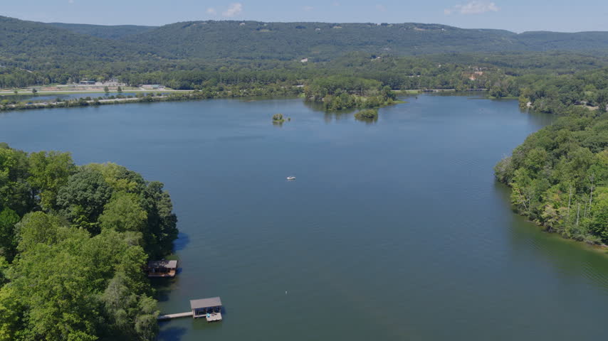 Aerial drone view of a broad lake near Chattanooga, Tennessee, with boat docks on a wooded shoreline, small islands and a long forested mountain ridge beyond.