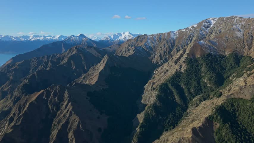 Aerial view of rugged mountain ridges and valleys near Lake Hawea, clear sky