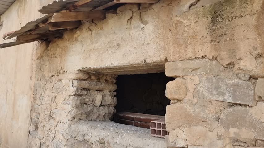 A small window of an old country house built of stone and mud bricks in a rural area, a traditional local architectural model.