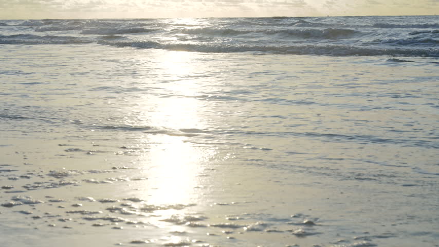 Waves lapping on the sand in Galveston, Texas in the golden hour light