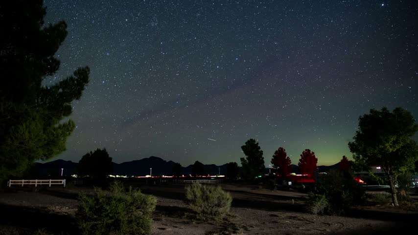 Time lapse of stars rising above a park near a highway at night