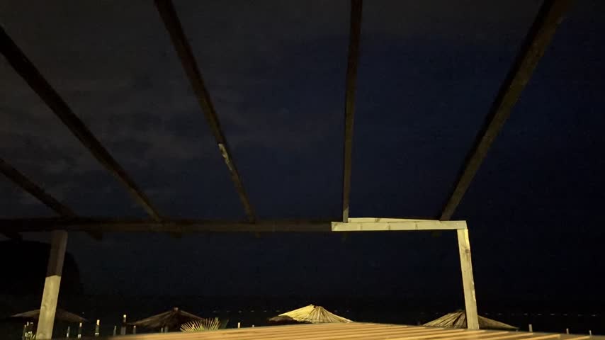 A dramatic time-lapse video capturing intense lightning strikes flashing across the dark night sky over the ocean. The electric discharges illuminate the storm clouds and reflect brilliantly on the surface of the sea, creating a mesmerizing visual display of nature