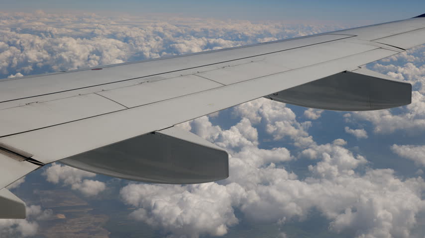Aerial view with airplane wing during flight above the clouds.
