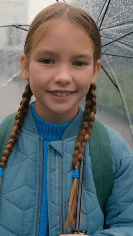 Portrait happy healthy Caucasian little school girl looking at camera smiling toothy holding umbrella at city rain weather cheerful daughter child learner kid pupil smile good mood enjoying raining