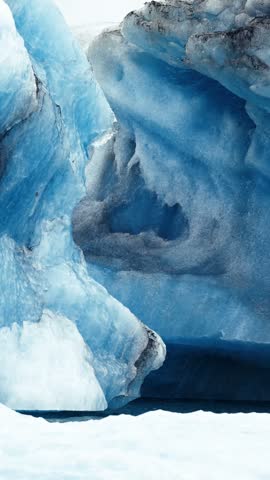 Weathered Arctic iceberg arch towers above dark Baffin Island water
