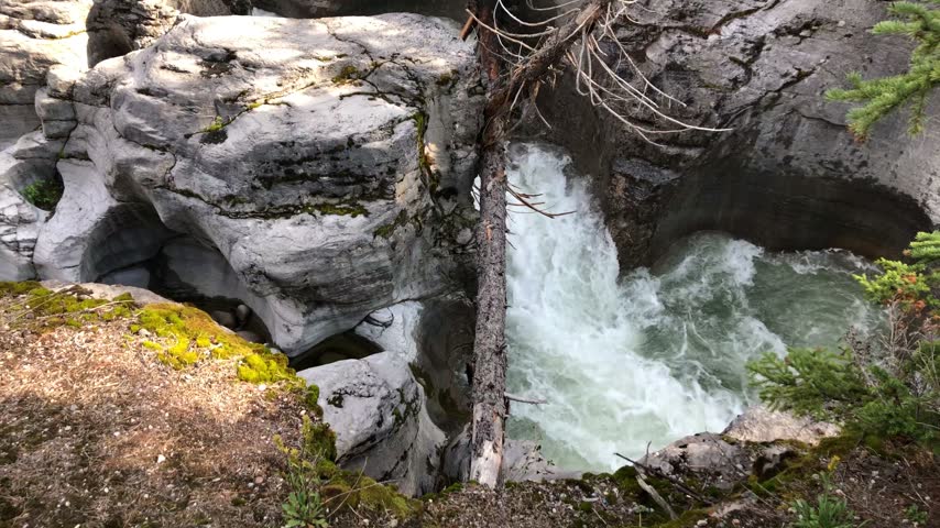 Foaming water flowing through a narrow rocky gorge in western Canada.