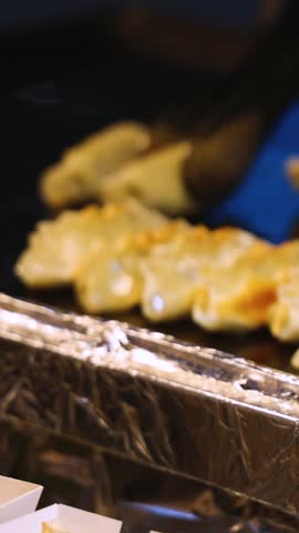 Mandu, Gunmandu, pan fried Korean dumplings in paper trays, variety of different traditional street food selection in Seoul, South Korea, night market with local vendor stalls cooking tasty dishes