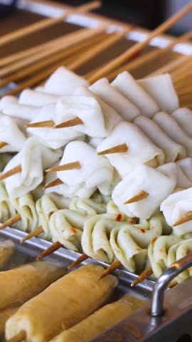Eomuk odeng, assortment of Korean fish cake skewers on display at a street food stall in Jung-gu, Busan, Yeongnam, South Korea, white, green and fried varieties on bamboo sticks at a night market
