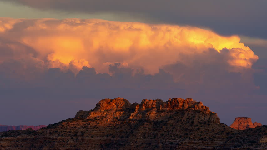 Colorful sunset timelapse as the desert cliffs fade from the sunlight and the clouds turn pink into dusk over the San Rafael Swell in Utah.