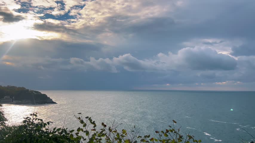 Thick storm clouds drift across windy coastal skies as late afternoon sun glints off choppy Black Sea waters in Zonguldak.