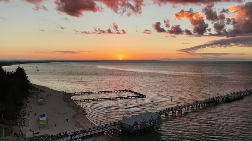 Drone footage of the timber jetty at Busselton in golden evening light, Western Australia. The underwater observatory sits at the far end of the pier. Geographe Bay stays calm through the evening.