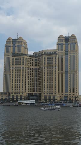 CAIRO, EGYPT - OCTOBER 2026: Motorboat sailing on the Nile River with Fairmont Nile City hotel skyscraper in the background