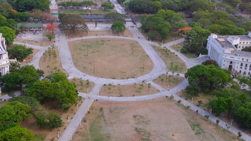 Scenic aerial pan over Rizal Luneta Park with green trees in Ermita, Manila Philippines