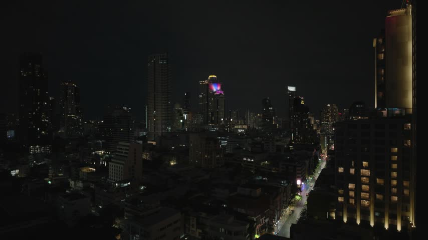 High angle view of illuminated skyscrapers and urban street traffic at night in Bangkok, Thailand