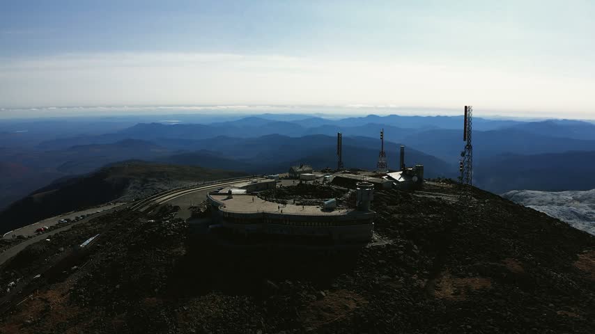 The summit monument at the top of Mount Washington New Hampshire with vast alpine mountain landscape
