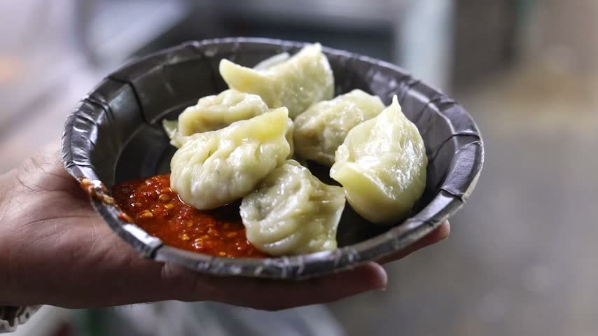 Momo or dumplings filled with vegetables or chicken inside and served with spicy red chilli sauce