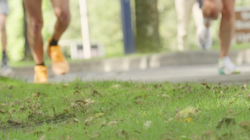 Runners Feet Jogging Past in Slow Motion with Shallow Depth of Field Blur.