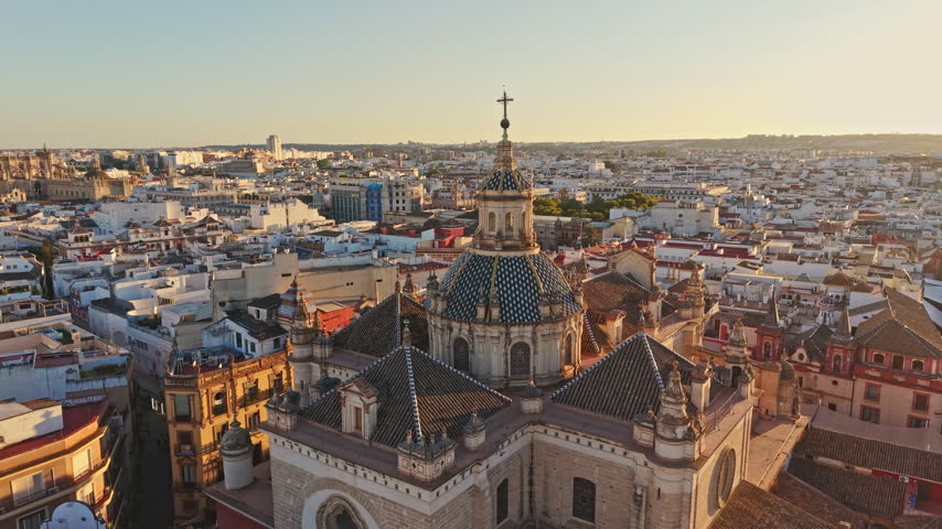 Aerial view of a Seville church dome with the cathedral and Giralda in the distance, Spain.