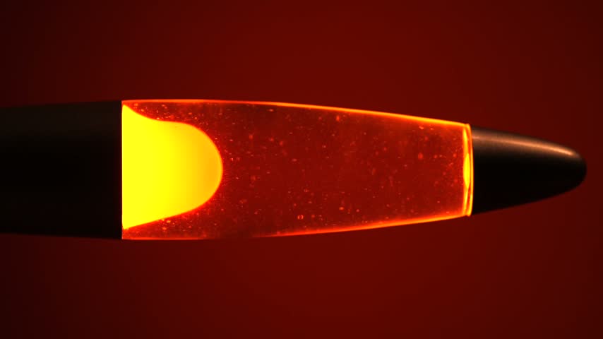 Close Up of Retro Lava Lamp with Rising and Falling Yellow Wax Blobs, Warm Orange Ambient Light and Red Background