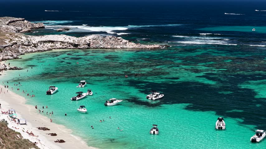 Aerial drone view of small boats moored in a reef lagoon at Rottnest Island, Western Australia. Dark reef patterns show through bright turquoise shallows.