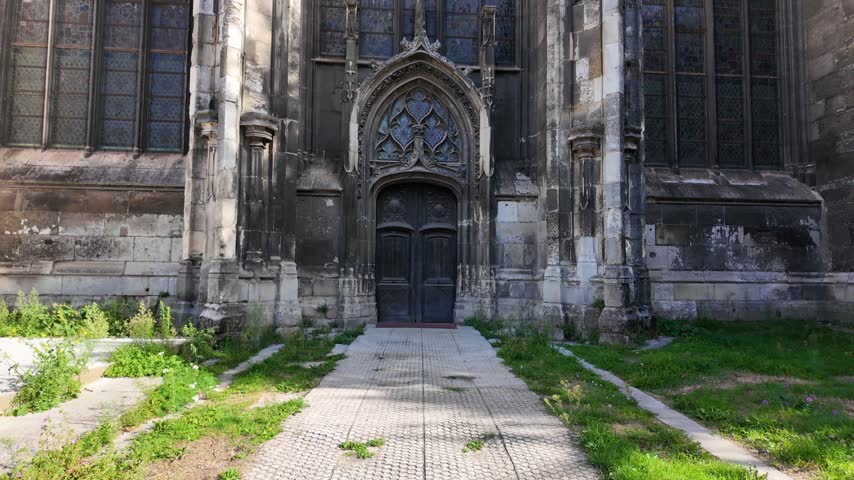 Gothic entrance of Abbatiale Saint-Ouen in Rouen, France with an ornate pointed arch, carved stone details and tall stained glass windows