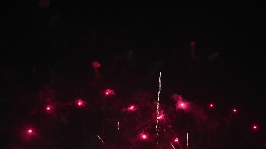 Vibrant red fireworks explode across the dark night sky with smoky textures, creating a festive background for Chinese New Year celebrations, Christmas, holiday events, and grand festivals