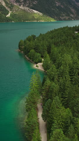 People Walk Along Mountainside Road Lined With Dense Trees Near Lake Achensee In Tyrol, Austria. Vertical, Aerial Shot