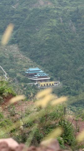 A traditional Chinese temple nestled amidst lush green mountain forests and terraced hillsides.