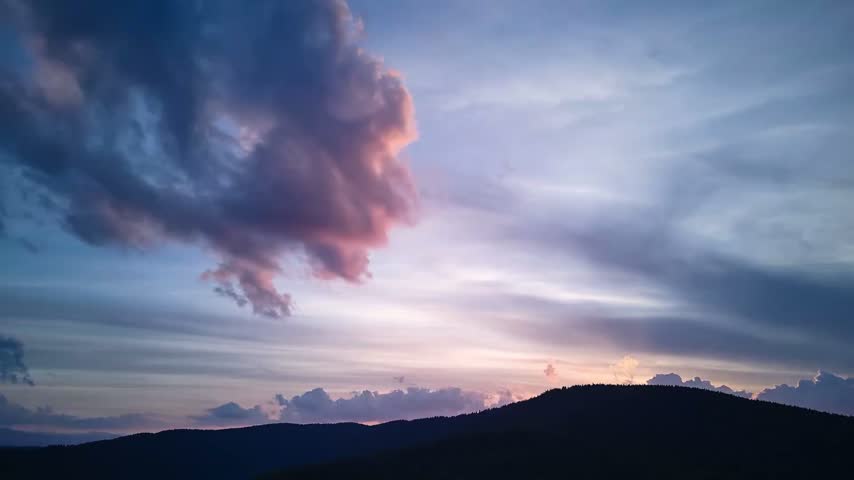 Sunset time-lapse over mountain ridge with colorful clouds in sky