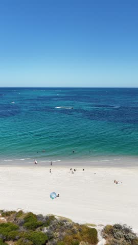 Aerial view of clear Indian Ocean water and pale sand near Perth, Western Australia. Dark reef shows through the shallows offshore. Perth