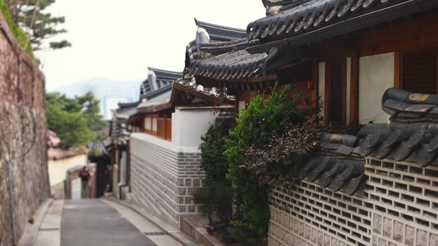 Bukchon Hanok Village in Gahoe-dong, Jongno-gu, Seoul, South Korea, street with traditional Korean hanok houses, giwa tiled roofs and white walls in a narrow alley on a sunny spring day