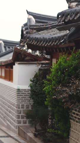 Bukchon Hanok Village in Gahoe-dong, Jongno-gu, Seoul, South Korea, street with traditional Korean hanok houses, giwa tiled roofs and white walls in a narrow alley on a sunny spring day
