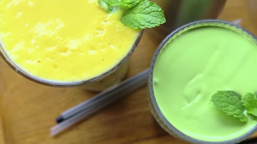 Creamy organic matcha green tea latte and mango smoothie in tall glasses.