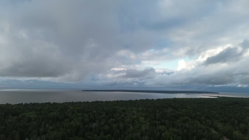 Sweeping drone panorama across a wide Manitoba lake, revealing miles of forested shoreline under soft cloudy skies. Calm freshwater stretches to the horizon. 4K aerial stock footage, Canada.