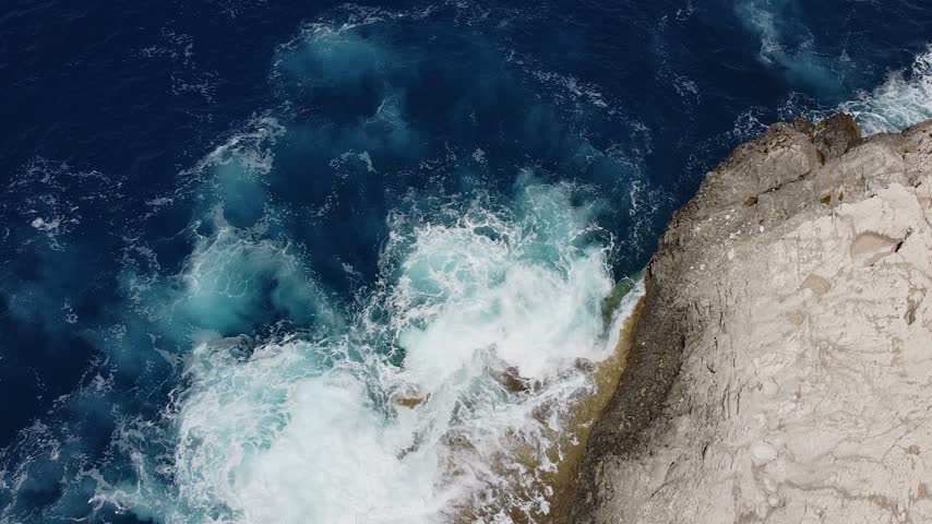 Foaming waves wash against pale rock along the rugged coast of Zakynthos, Greece.