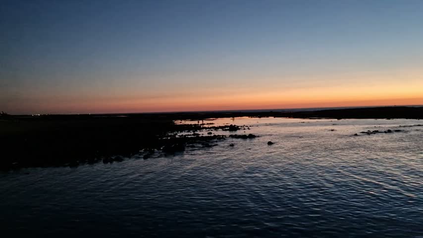 ​Beautiful sunset over the ocean sea with calm waves and orange sky.